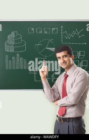 Businessman giving presentation on blackboard and pointing upward Stock Photo