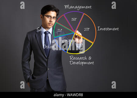 Young businessman touching a pie chart on a touch screen Stock Photo