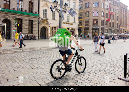 Man on a bike cycle delivering takeaway food for Uber Eats in the market square of the Polish city of Wroclaw Stock Photo