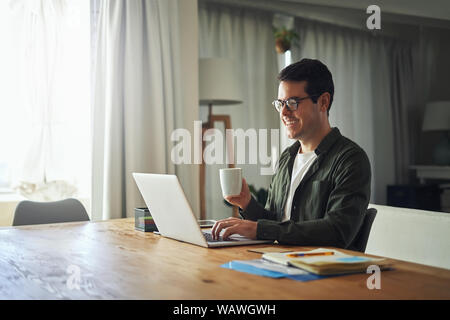 Smiling man at home working on laptop online at home Stock Photo