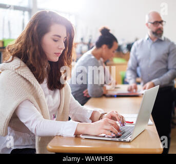 Beautiful girl using laptop in an auditorium. Stock Photo