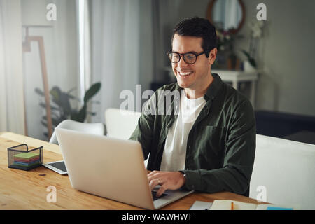 Happy man wearing eyeglasses using laptop at home Stock Photo