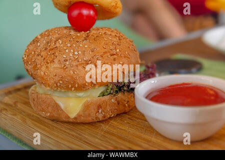 Fresh tasty burger and tomato on wooden table Stock Photo