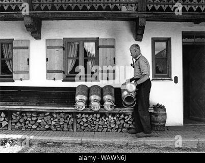 Old man drying milk cans in front of his farm, shoemaker Cajetan Anker, around 1960, Oberaudorf, Upper Bavaria, Bavaria, Germany Stock Photo