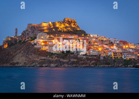 Colorful houses on the hillside with a fortress on the top. Night panorama of medieval town Castelsardo, Sardinia, Italy. Beautiful, calm evening. Pop Stock Photo