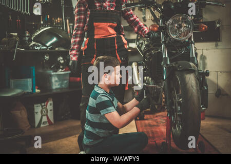 African american woman mechanic repairing a motorcycle in a workshop. Stock Photo