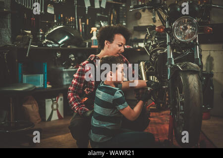 African american woman mechanic repairing a motorcycle in a workshop. Stock Photo