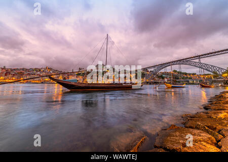 view across the Rio Douro at dusk to Porto with traditional port boats in the foreground. Stock Photo
