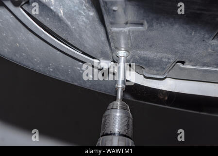 Mechanic at work. Attach a screw with the cordless screwdriver Stock Photo