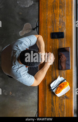High angle view of Asian businessman using tablet next to smartphone Stock Photo