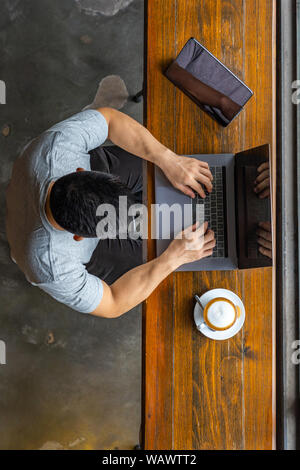 Vertical photo of young Asian man freelancing on laptop  Stock Photo