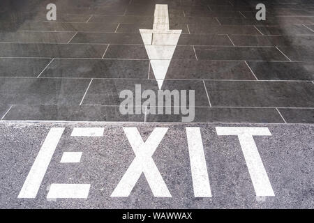 Exit text with arrow painted on the floor of underground parking exit Stock Photo