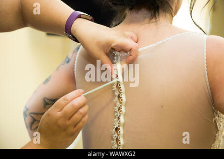 Wedding dress being done up on a Brides wedding day, close up of wedding dress being done up before the ceremony Stock Photo