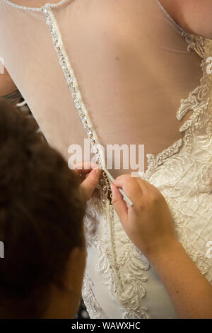 Wedding dress being done up on a Brides wedding day, close up of wedding dress being done up before the ceremony Stock Photo