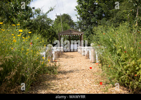 outside wedding arbour in the summer, surrounded by wildflowers waiting for the guests and bride and groom to arrive for the wedding ceremony Stock Photo