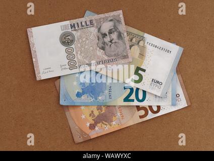 MASSA CARRARA, ITALY - AUGUST 14, 2019: Italian vintage and obsolete Lire note overlays and part obscures new Euro currency. Stock Photo