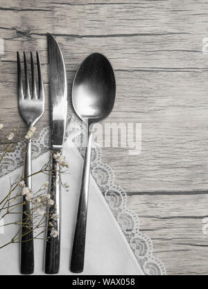 Light pastel colored tableware set: plate, vintage silverware on napkin and delicate pink roses on rustic shabby wooden background with copy space Stock Photo