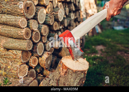 Senior man chopping firewood with an axe in countryside yard. Stock Photo