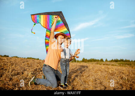 Father with son launching colorful air kite on the field. Concept of a happy family having fun during the summer activity Stock Photo