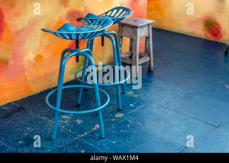 Two blue painted metal stools and a weathered wood stool next to