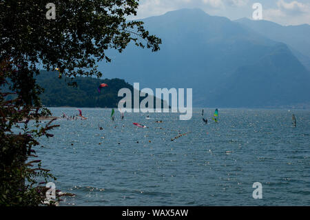 Lake Como, Italy - July 21, 2019: View of mountain lake with windsurfers training on a sunny summer day. District of Como Lake, Alps, Colico, Italy