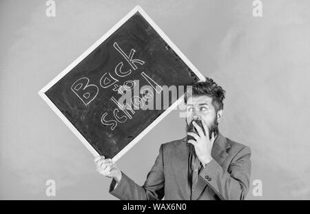 Keep working. Teacher with tousled hair stressful about school year beginning. Teaching stressful occupation. Teacher bearded man holds blackboard with inscription back to school green background. Stock Photo