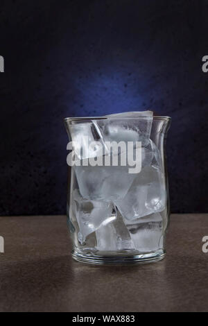 Glass with ice in a bar, dark environment as part of low key light photography Stock Photo