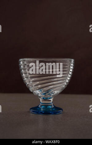 Empty cup glass on a table in a dark environment, with black background, low key light photography Stock Photo