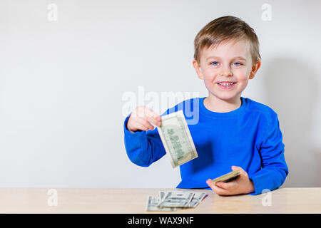 Happy child with money dollar, little businessman. Pile of United States dollar hundred USD banknotes in boy's hand. Stock Photo