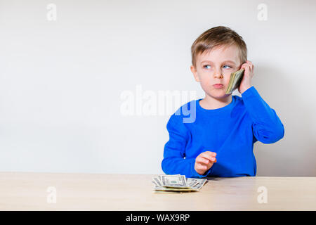 Happy child with money dollar, little businessman. Pile of United States dollar hundred USD banknotes in boy's hand. Stock Photo