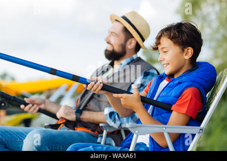 Son feeling excited while fishing for the first time with daddy Stock Photo