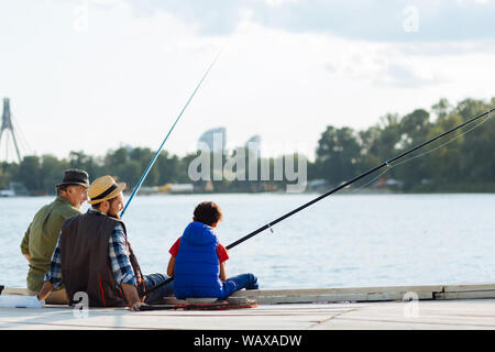 Boy feeling memorable while fishing with dad and granddad Stock Photo