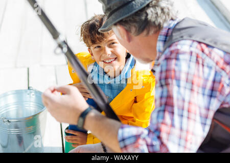 Handsome smiling dark-eyed boy fishing with grandfather Stock Photo