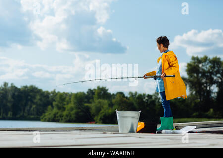 Boy wearing bright green rain boots standing and fishing Stock Photo