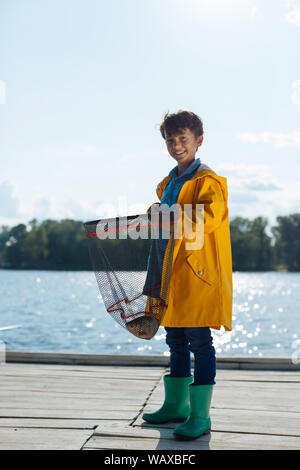 https://l450v.alamy.com/450v/waxbfc/cheerful-boy-wearing-raincoat-holding-fishing-net-waxbfc.jpg