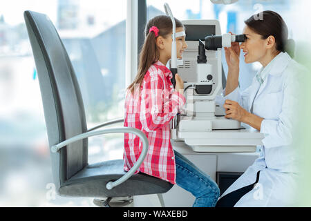 Nice professional doctor checking the girls eyesight Stock Photo
