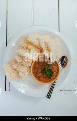 Thai crispy rice cake with shrimp tammarind peanut sauce - Thai traditional snack in white plate on white table. Top view shot Stock Photo