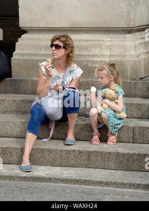 Mum & daughter eating ice cream, little girl holding teddy bear. Stock Photo