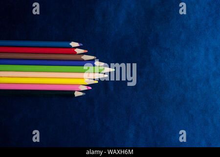 Flat lay composition for Teacher's Day with colored pencils on a blue textured board with copy space. Stock Photo