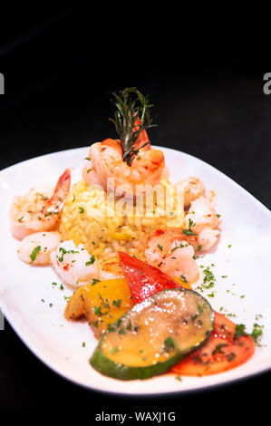 Saute shrimps, scallop, squid with pepper chilli with Mediterranian roast vegetable and saffron rice on white plate dark background Stock Photo