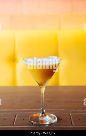 Sweet mango juice smoothie in beautiful cocktail glass on wood table with bright yellow colour background Stock Photo