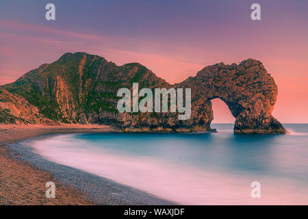Sunset at Durdle Door (sometimes written Durdle Dor), a natural limestone arch on the Jurassic Coast near Lulworth in Dorset, England. Stock Photo