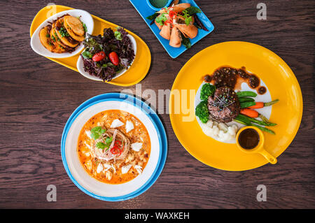 Delicious Foods on colorful dishes on wood table. Stock Photo