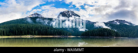 Montenegro, XXL panorama of durmitor mountains and black lake water surrounded by green coniferous forest in national park near zabljak Stock Photo