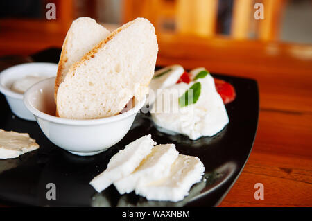 Baguette bread toast  slices and fresh mozzarella and assorted buffalo milk cheese in black plate Stock Photo