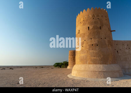 Wide-angle view taken at sunset of one of the towers of the Al Zubarah fort, Qatar Stock Photo