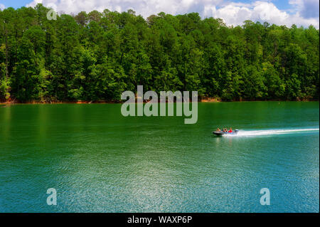 Bryson, North Carolina, USA - August 3, 2019:  A boat runs along the waters of Nantahala Lake seen from a moving train. Stock Photo