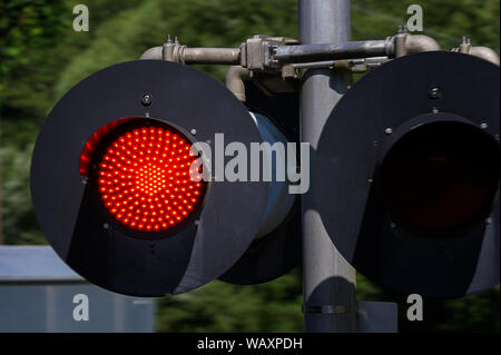 Close up of a red railroad crossing traffic light seen from a moving train. Stock Photo