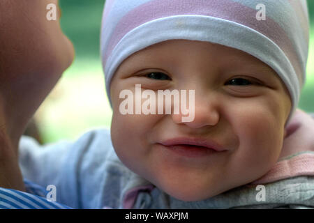 Mom walks with the baby in the park. The child in his arms close-up. Spring Stock Photo