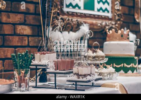 Selective focus shot of green sticks, souffles, cupcakes and a decorated cake on white table Stock Photo
